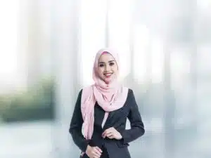 A woman wearing professional attire in hijab at the surroundings of a business school.